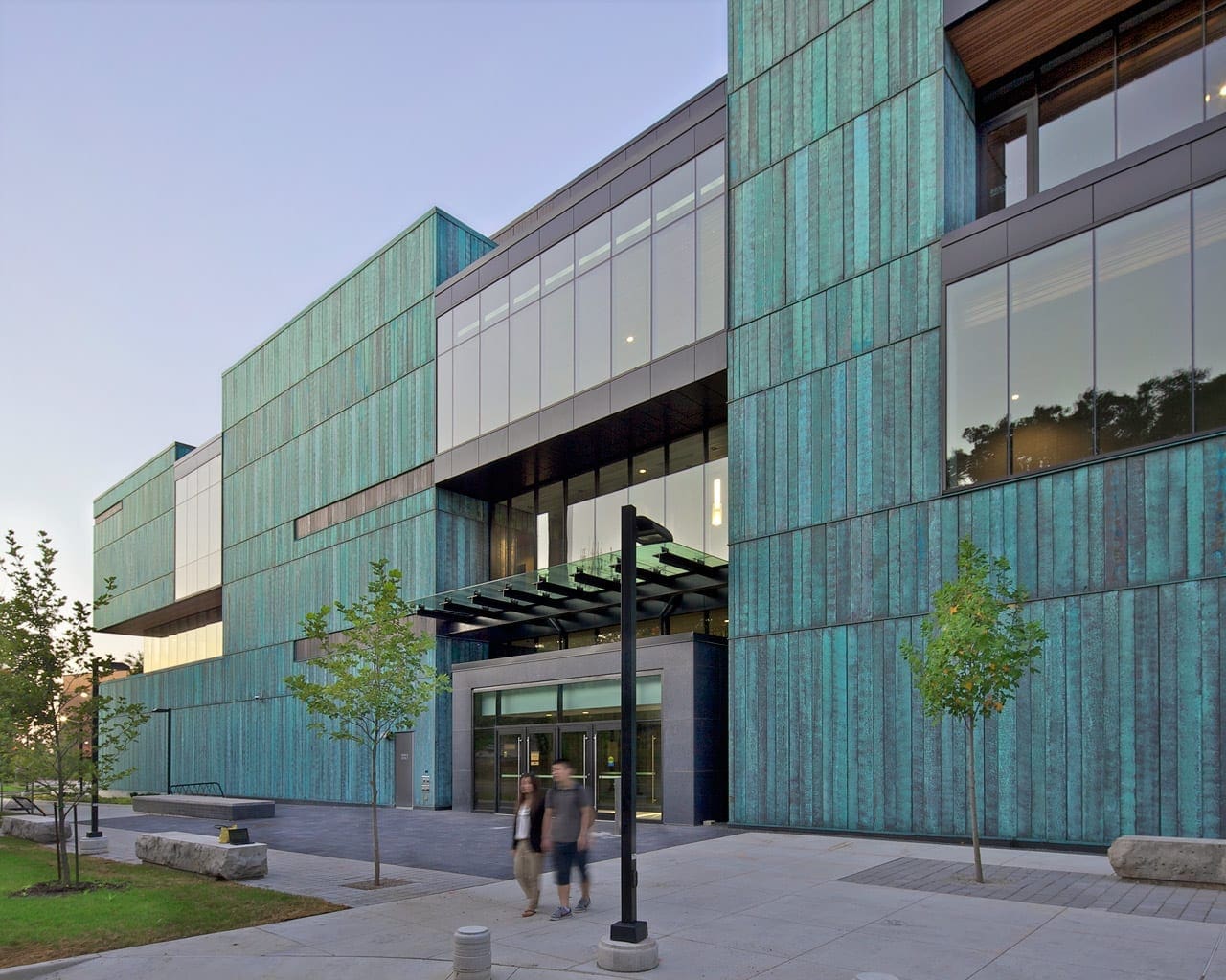 Students walking at dawn amidst the blue copper facade.