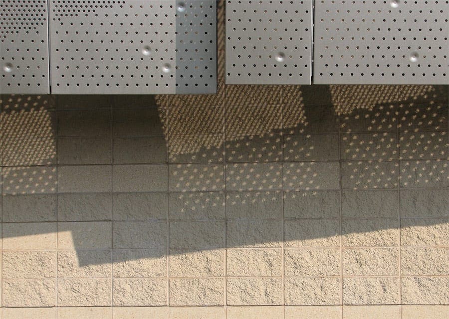 Detail of the facade and shadows cast through the perforated metal.