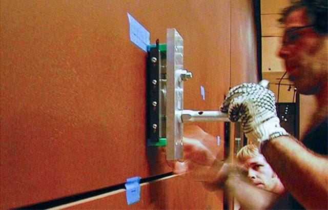 A museum installer places a custom-magnet wall connection to hang a painting.